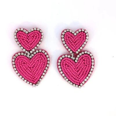 Afbeelding van Oorknopjes met 2 hangende hartjes gemaakt van fuchsia roze kraaltjes afgezet strass