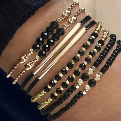 Afbeelding van set van 8 armbanden met zwarte kralen voor dames, goudkleurige accenten en koorddetails elastische dames